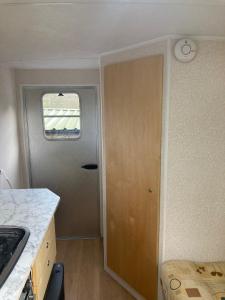 a kitchen with a door with a clock on the wall at Beautiful Tiny house on wheels in Norwich