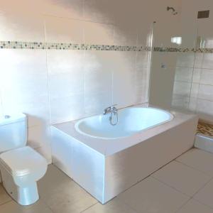 a white bathroom with a tub and a toilet at Sensual Sanctuary Boutique Spa in Witbank