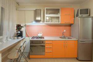 a small kitchen with orange cabinets and a refrigerator at Central Barkar Apartments in Odesa