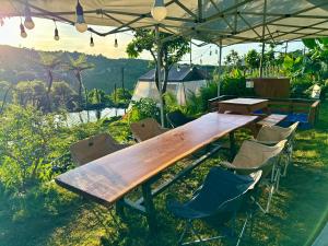 a wooden table and chairs under an umbrella at Mầm Farmstay and Camping in Lam Ha