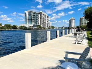 a dock with chairs and the water with buildings at Renovated Intercoastal 2Bdrm 1 bath condo Walk to Beach in Fort Lauderdale
