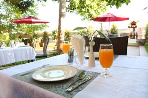 a table with a plate and two glasses of orange juice at Villa Ang Thong in Luang Prabang