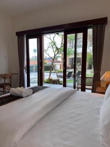 a bedroom with a large white bed with sliding glass doors at Omah Santai Canggu in Canggu +10 photos