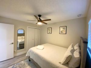 a bedroom with a bed with a ceiling fan at Cozy Coral Cottage with Tiki Hut, Mini Golf, Arcade and Grill in Cape Coral