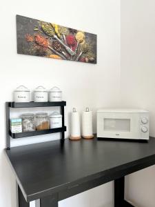 a black table with a microwave and a painting at Keja Rooms II - Pokoje Noclegi w Centrum Gdyni in Gdynia +39 photos