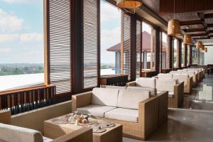 eine Reihe von Stühlen und Tischen in einem Zimmer mit großen Fenstern in der Unterkunft Kamala Bali Resort in Nusa Dua