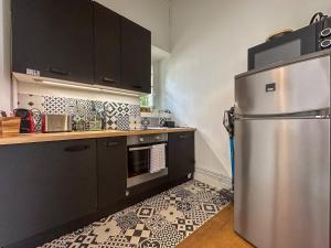 a kitchen with a stainless steel refrigerator and black cabinets at Le jardinet de la cathédrale in Chartres