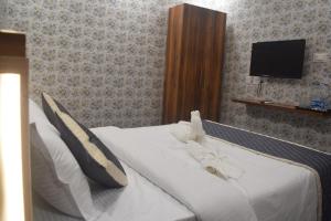 a bedroom with a white bed with a tv on the wall at Esakki Empire in Chennai
