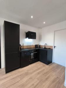 a kitchen with black cabinets and a black refrigerator at Sublime T2 en plein centre climatisé in Montélimar +12 photos