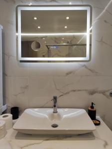 a white sink in a bathroom with a mirror at Lydia Luxury Apartment by the Sea in Perea +8 photos