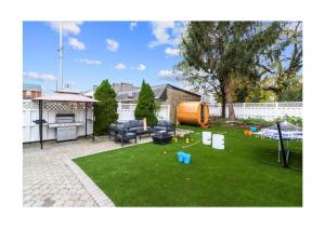 a backyard with a lawn with a grill and a table at Epic Spa & Play Retreat NYC EWR Sleeps 30! in Bayonne