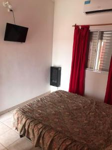 ein Schlafzimmer mit einem Bett mit roten Vorhängen und einem Fernseher in der Unterkunft Deptos Peumayen - Parking - Excelente Ubicacion - Full Equipado in Río Colorado