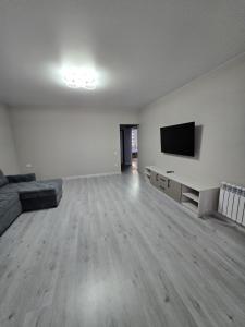 an empty living room with a couch and a flat screen tv at Новая квартира в 10 минутах от центра города in Qŭyliq