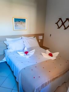 a white bed with two red flowers on it at Prive de Veraneio in Porto De Galinhas