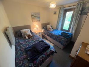 a small bedroom with two beds and a window at Tarnside Cottages in Brampton