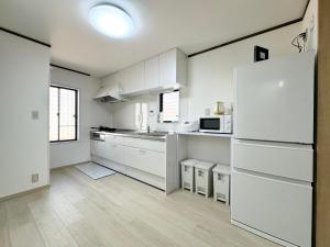 东京Family House 蕾 池袋徒步圈全新装修日式户建民宿的厨房配有白色橱柜和白色冰箱
