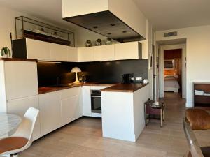 une cuisine avec des armoires blanches et une table et des chaises dans l'établissement T3 vue port 200m de la plage 2 chambres avec garage, à Carnon-Plage