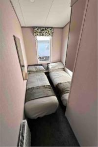 a row of beds in a room with a window at BRAND NEW 6 berth holiday home in Selsey
