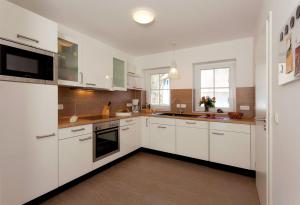 a large white kitchen with white cabinets and appliances at Haus 163, Lärchenweg 8 in Ostseebad Karlshagen