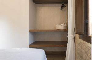 a bedroom with a white bed and wooden shelves at O Fogar da Pequena Galia in Caldas de Reis