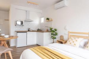 a white bedroom with a bed and a kitchen at Estudio Bianca in L'Escala