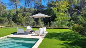a patio with chairs and an umbrella next to a pool at TRES TEULADES 8+1 in Castellnou de Bages