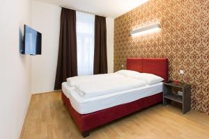 Schlafzimmer mit einem Bett mit rotem Kopfteil und einem TV in der Unterkunft Vienna Stay Apartments Tabor 1020 in Wien