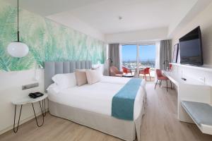 a hotel room with a large bed and a desk at Hotel Cristina by Tigotan Las Palmas - Adults Only in Las Palmas de Gran Canaria