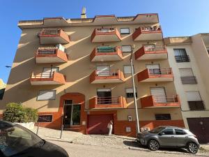 un edificio con balconi e una macchina parcheggiata di fronte di Dias Incríveis na Costa da Caparica a Quinta de Santo António Altre 3 foto