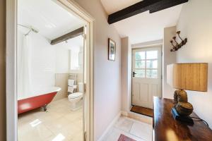 a bathroom with a tub and a toilet and a sink at Strand Cottage in Burton Bradstock +33 photos