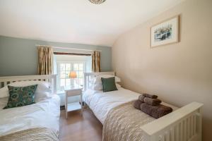 a bedroom with two beds and a desk at Strand Cottage in Burton Bradstock