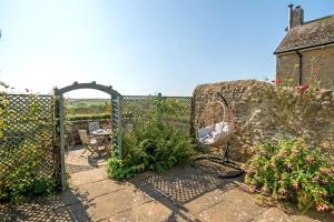 a garden with a gate and chairs and flowers at Strand Cottage in Burton Bradstock