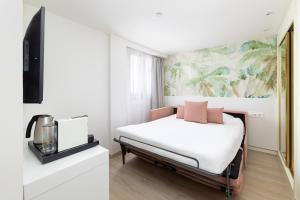 a bedroom with a bed with pink pillows on it at Hotel Cristina by Tigotan Las Palmas - Adults Only in Las Palmas de Gran Canaria