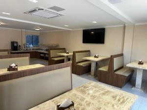a restaurant with tables and chairs and a television at Hotel Planaltina in Planaltina