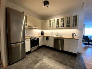 a kitchen with white cabinets and a stainless steel refrigerator at 4-room spacious condo w patio in Reykjavík