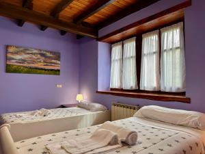 two beds in a room with purple walls and windows at Kanala, estupendas vistas al Urdaibai in Canala