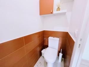 a white toilet in a bathroom with brown tiles at ModernCosy Près Disneyland Paris in Noisy-le-Grand