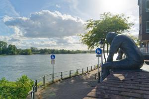 a statue of a woman sitting on the side of a river at Ferienwohnung Little Dragon - Rheinblick in Rees