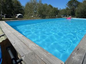 una grande piscina blu con un ponte di legno di FLOR La Roulotte du Médoc a Naujac-sur-Mer