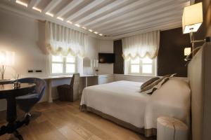 una camera con letto bianco, scrivania e sedie di Albergo Celide a Lucca
