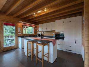 a kitchen with white cabinets and a island with bar stools at Le Grand Chalet Bellevue - parking Wifi BBQ in La Bresse +13 photos