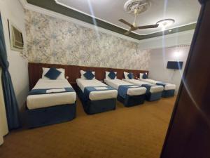 a room with a row of beds with blue pillows at فندق برادايس نيس النزهة Paradise Nice Hotel in Mecca +41 photos