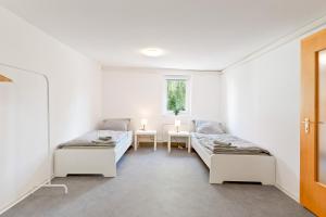 two beds in a room with a table and a window at Perfekt für Firmen und Gruppen - 1 Haus, 2 XXL Wohnungen in Göppingen