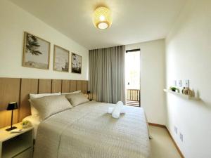 a bedroom with a white bed and a window at Bangalô Exclusivo A6 Imbassaí Privilege Beira Mar in Imbassai