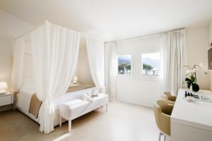 a white room with a bed and a couch and a window at Baia Bianca Suites in Portoferraio +80 photos