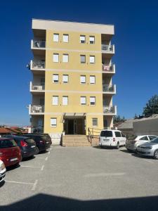 a yellow building with cars parked in a parking lot at Altina Gottfried Studio in Novi Grad