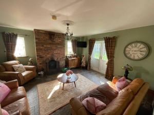 a living room with a couch and a clock on the wall at Eastfield Cottage Free Parking And Ev Charger in Leven