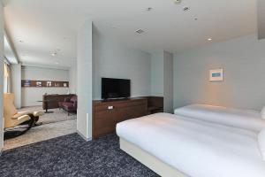 a hotel room with two beds and a flat screen tv at JR Kyushu Hotel Miyazaki in Miyazaki