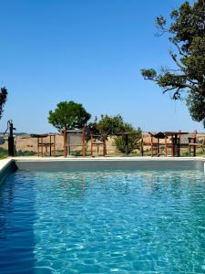 a swimming pool with blue water and picnic tables at Agriturismo Re Tarquinio in Tuscania