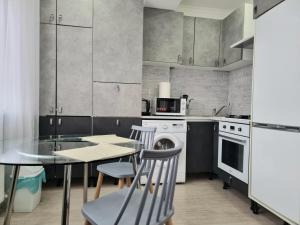 La cocina está equipada con mesa, sillas, fogones y horno. en Botanical Garden Park Apartment, en Chişinău 2 fotos más
